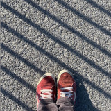 Schuhe auf Asphalt. Grafisch mit schrägen Linien durch Schatten