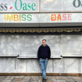 Sven vor einem geschlossenen Kisok, der Imbiss Oase heißt